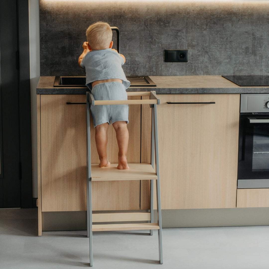 Child standing on a grey kitchen tower in a modern kitchen