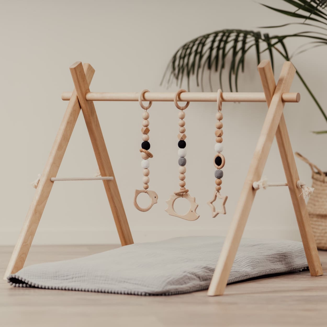 Wooden baby gym frame with wooden toys hanged on it and place set for playtime