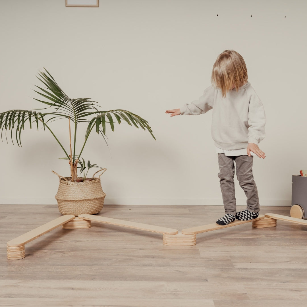 Child walking on wooden balance beam path for kids, indoor balance activity
