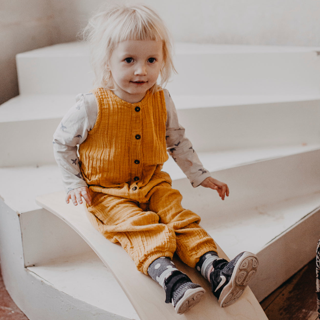 Child sliding down the balance board that is used as an indoor slide.