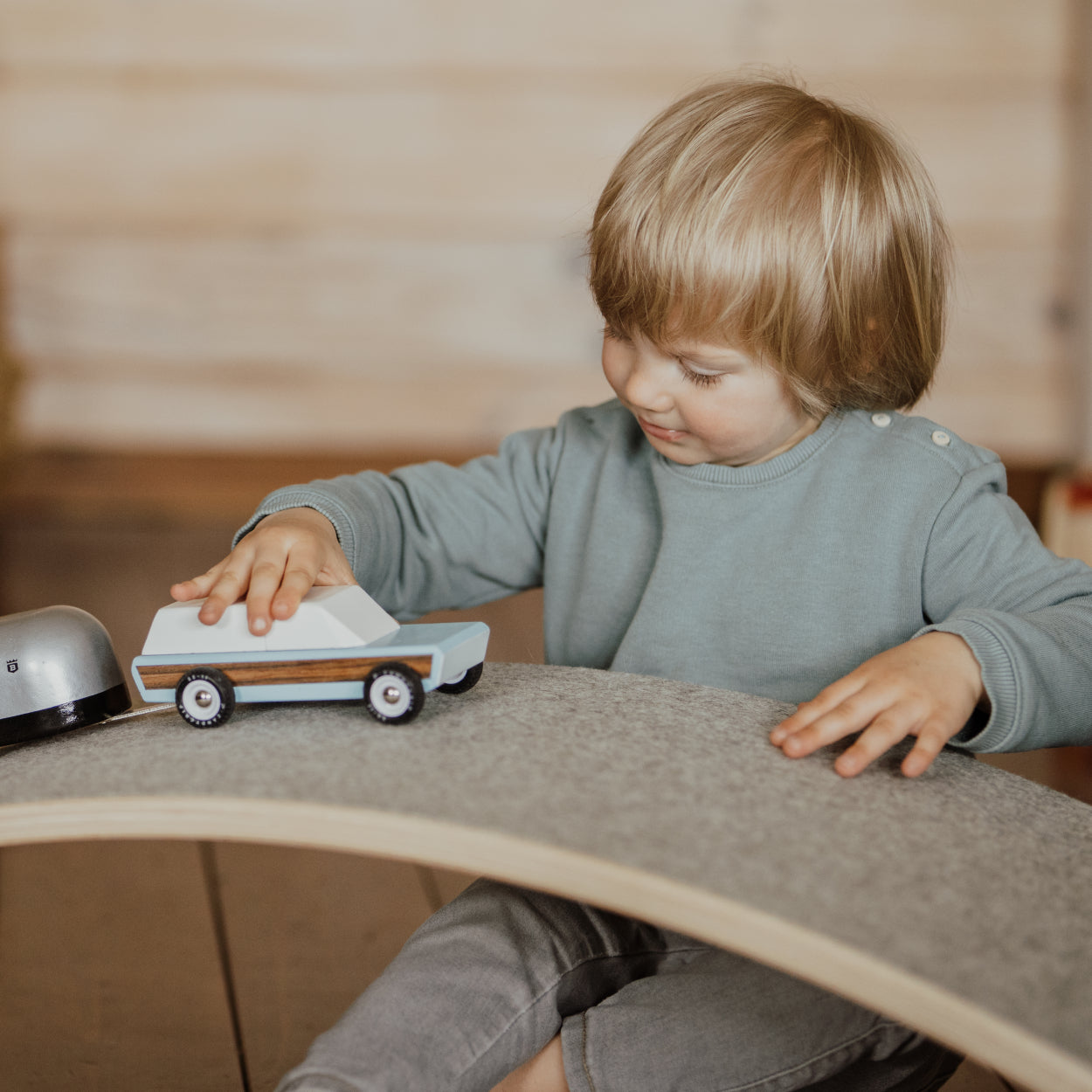 Child using balance board as a race track for a car for the playtime. 