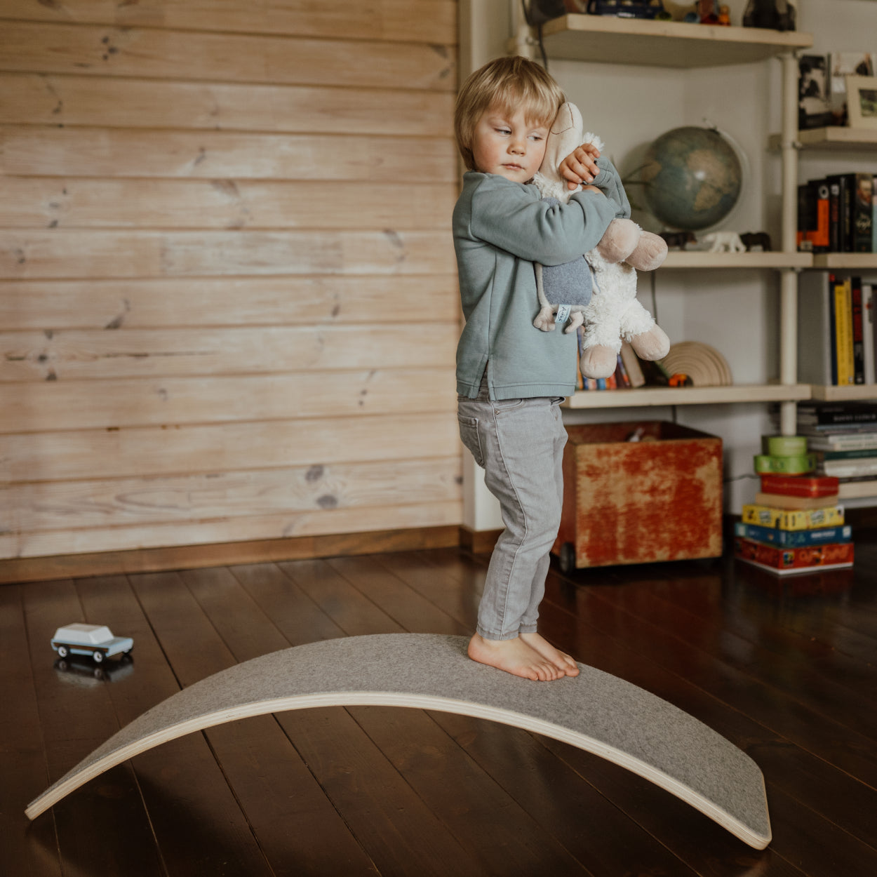 Boy standing on upside down placed balace board with soft felt bottom. 