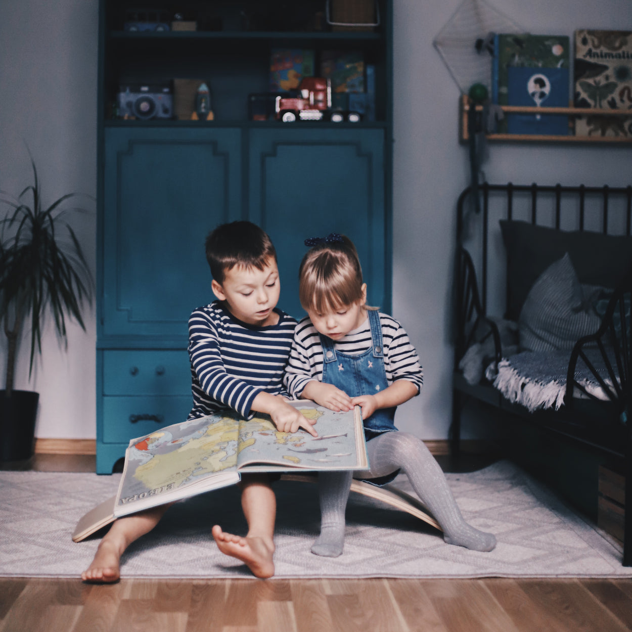 Children sitting on wooden wobbly board turned upside down and reading a book