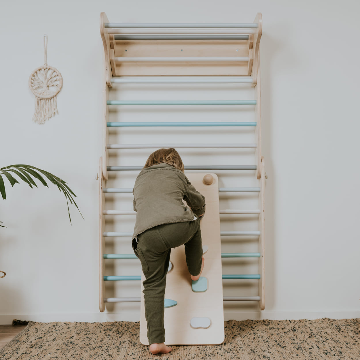 Child enjoying wooden ramp attached to Swedish wall climber gym.
