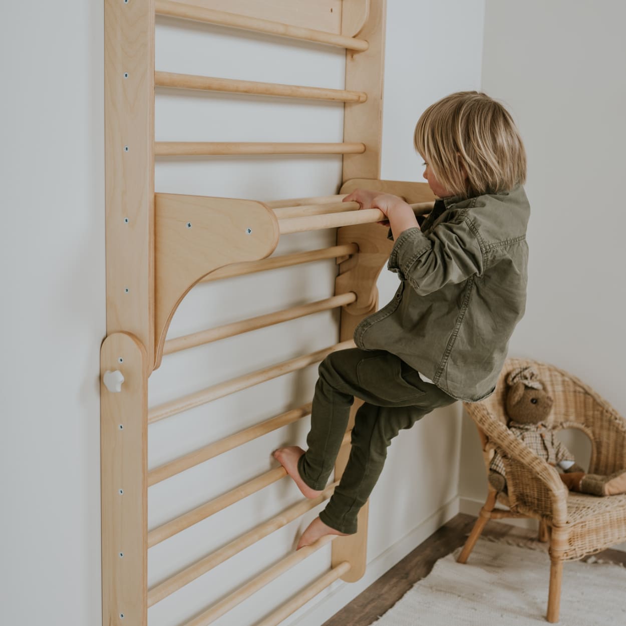 Child  climbing on wooden Swedish ladder climber set. 