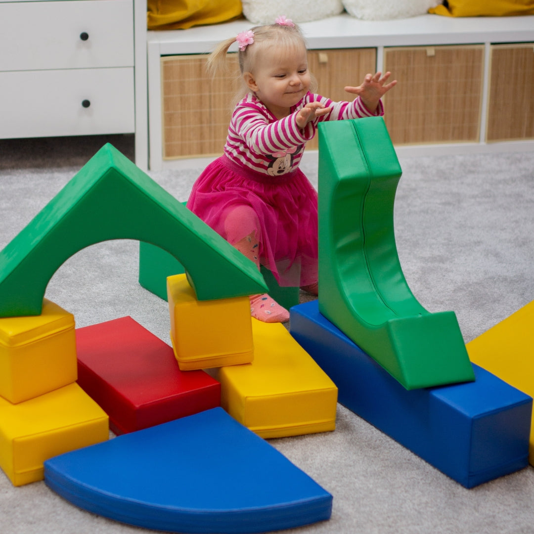 Toddler playing on multicolor soft play Creativity blocks featuring arch and slide elements