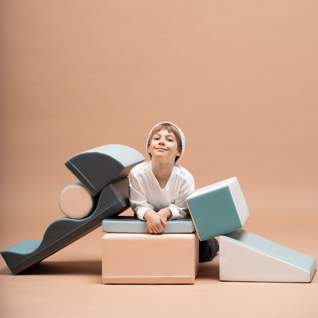 Child sitting among Discoverer pastel soft foam blocks, exploring play structures with joy