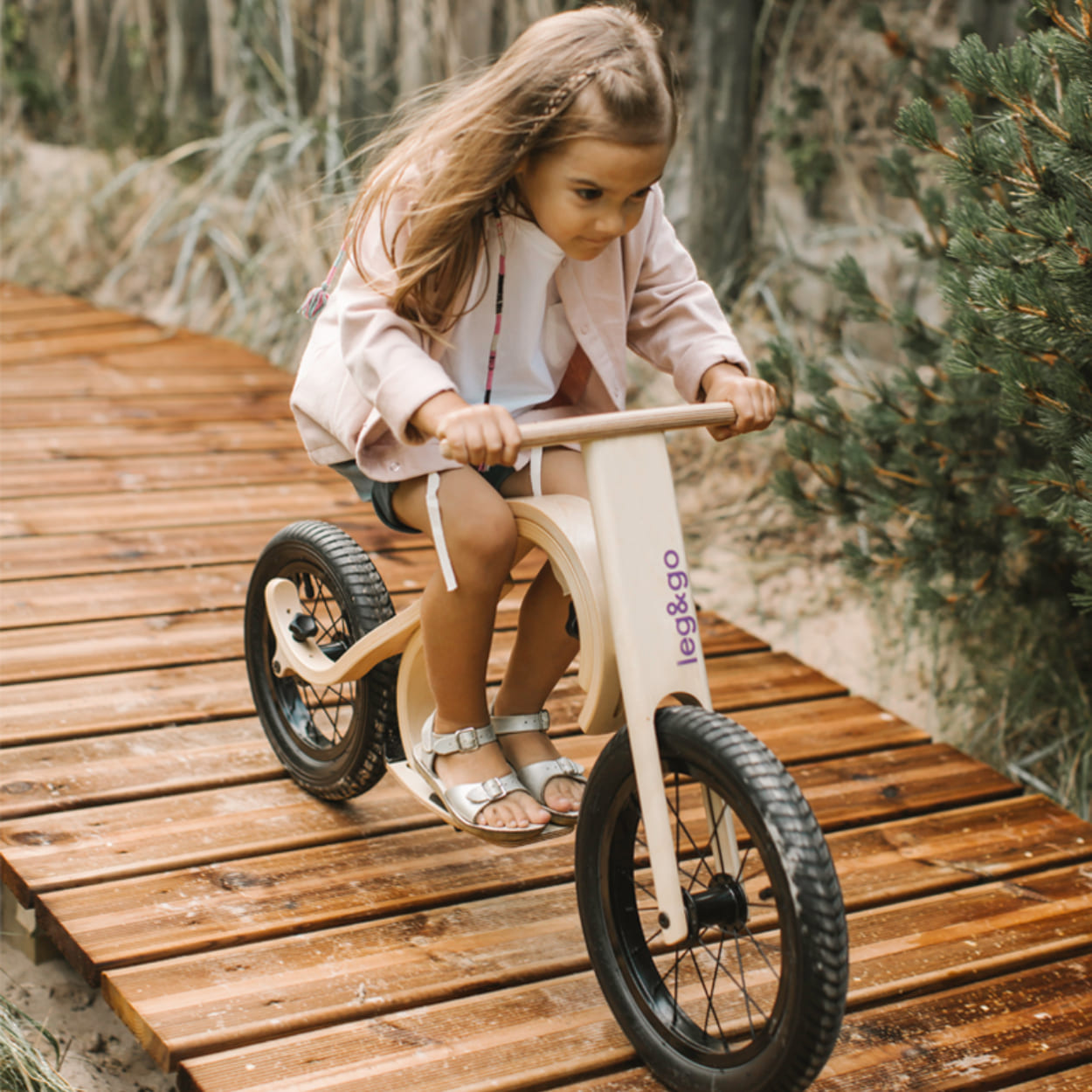 Girl riding leg&go balance bike with downhill add on attached