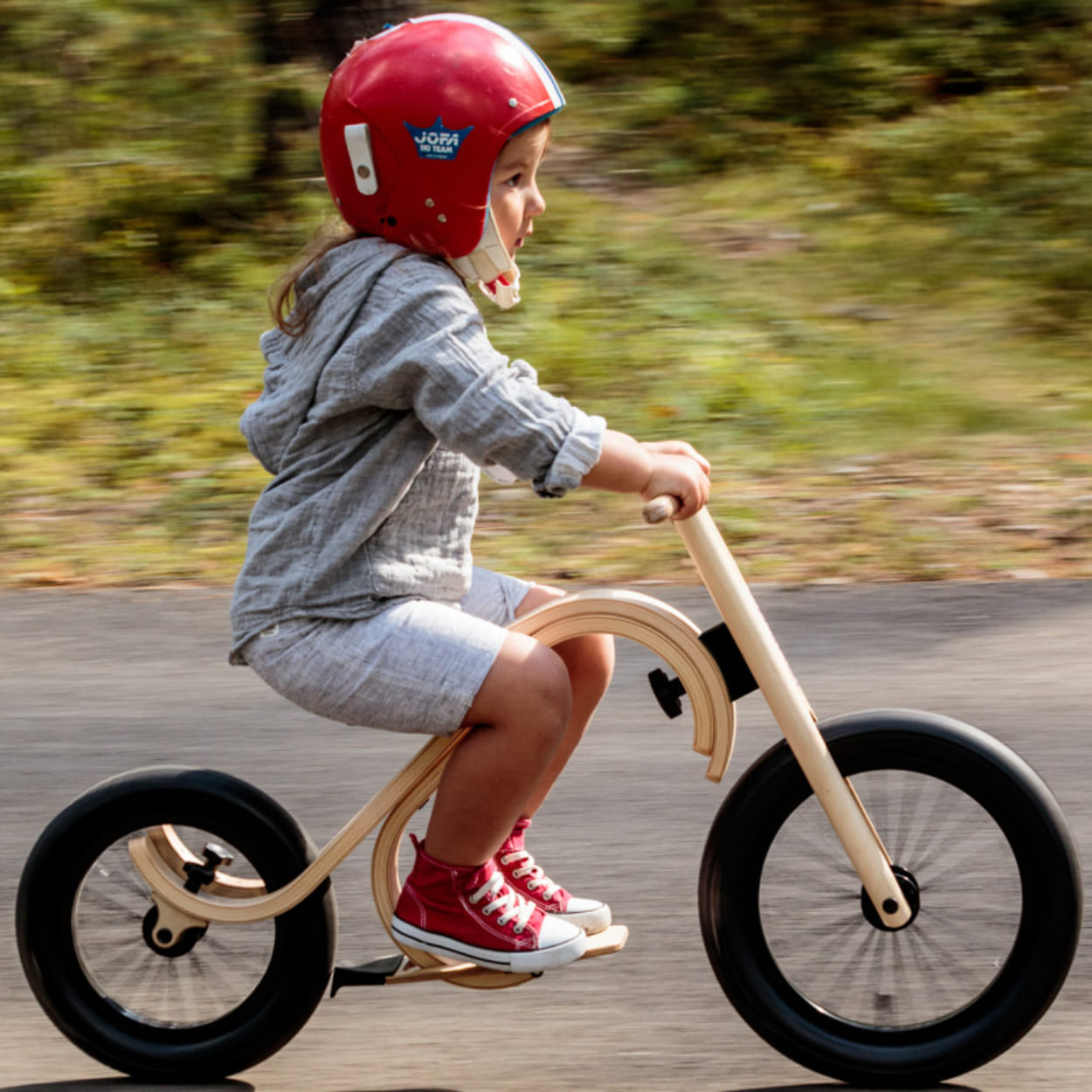 Child riding wooden bike in sunny weather
