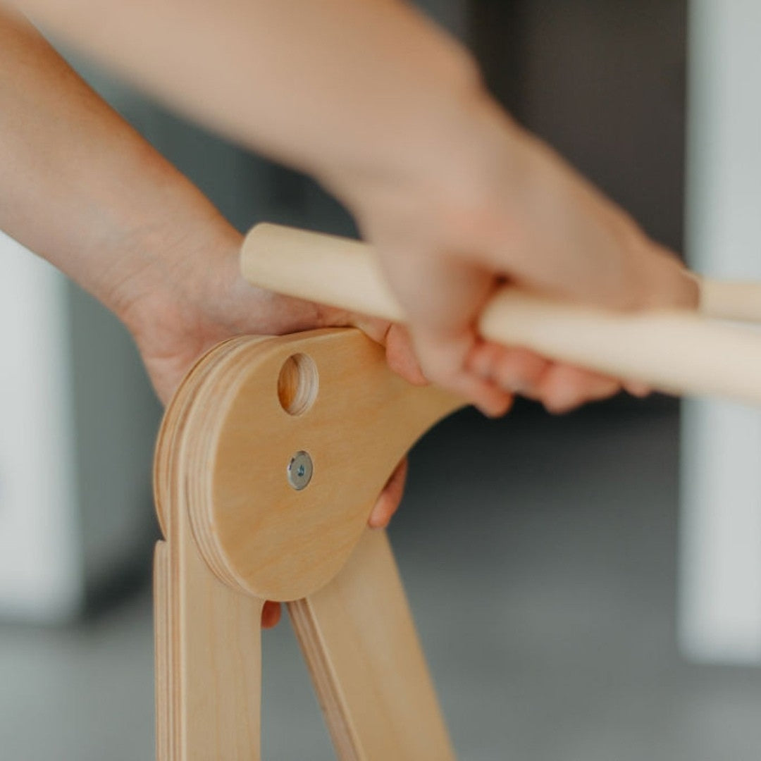 Close-up of hands assembling a wooden helper tower, demonstrating how the safety rail can be removed