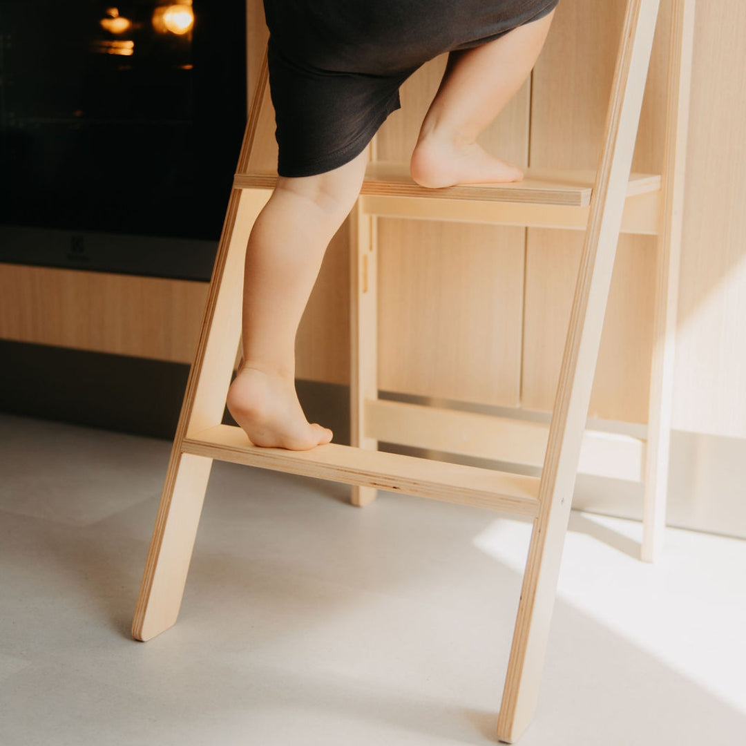 Child climbing on a natural colored kitchen tower to safely reach the countertop