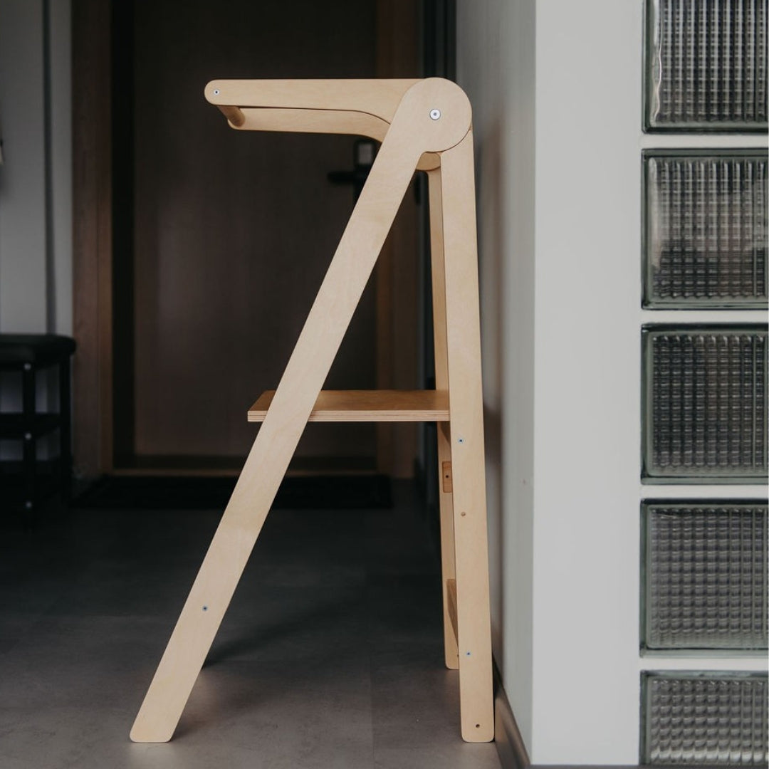 Wooden kitchen helper tower step stool against a wall