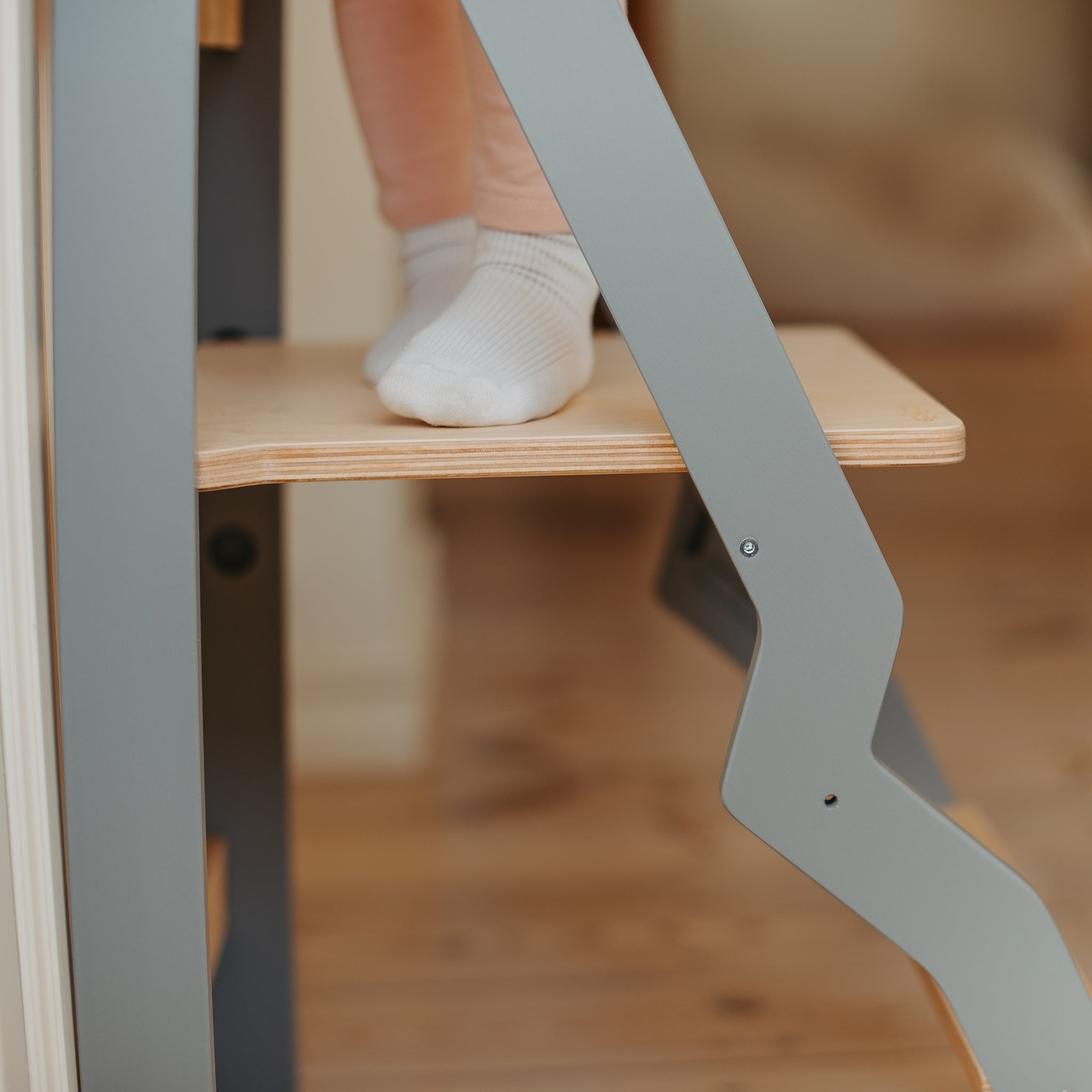 angled leg detail of gray wooden helper tower for toddlers