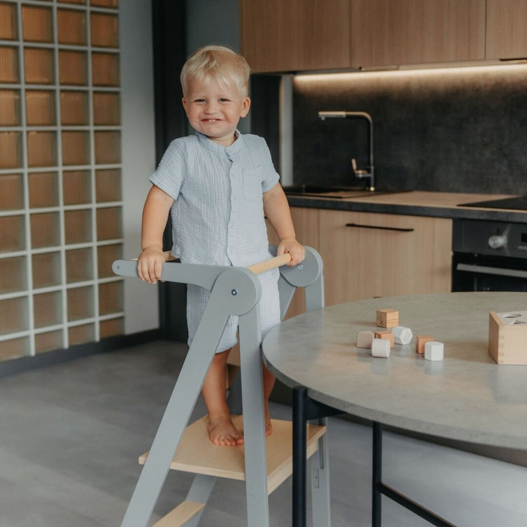 Child playing with wooden blocks on kitchen counter using Leg&Go Foldable Helper Tower Gray