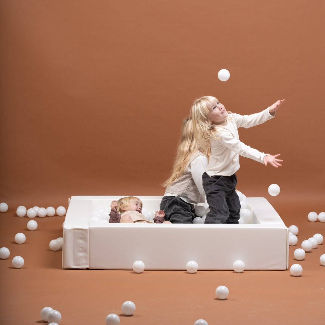 Three children playing with white balls on a brown background
