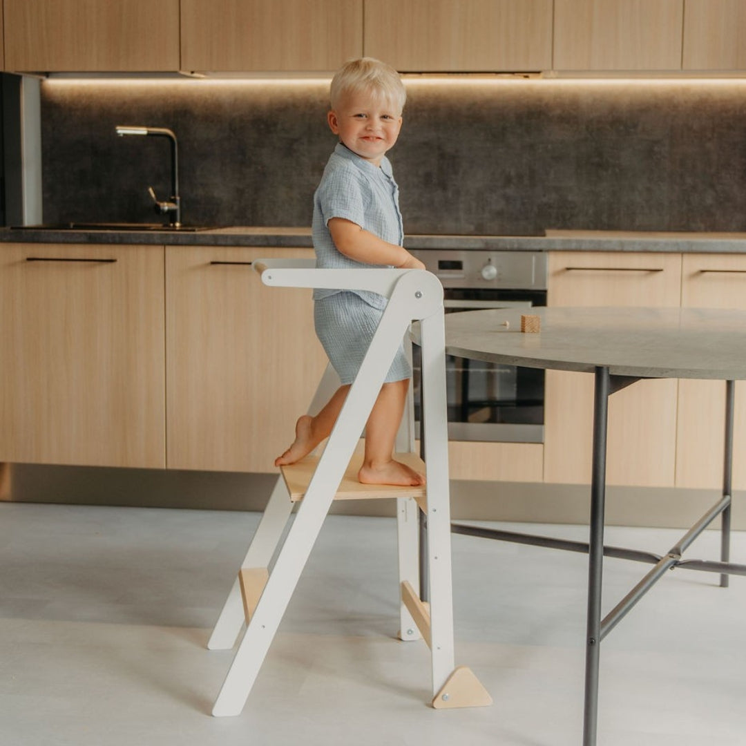 Child standing on a white kitchen tower in a modern kitchen