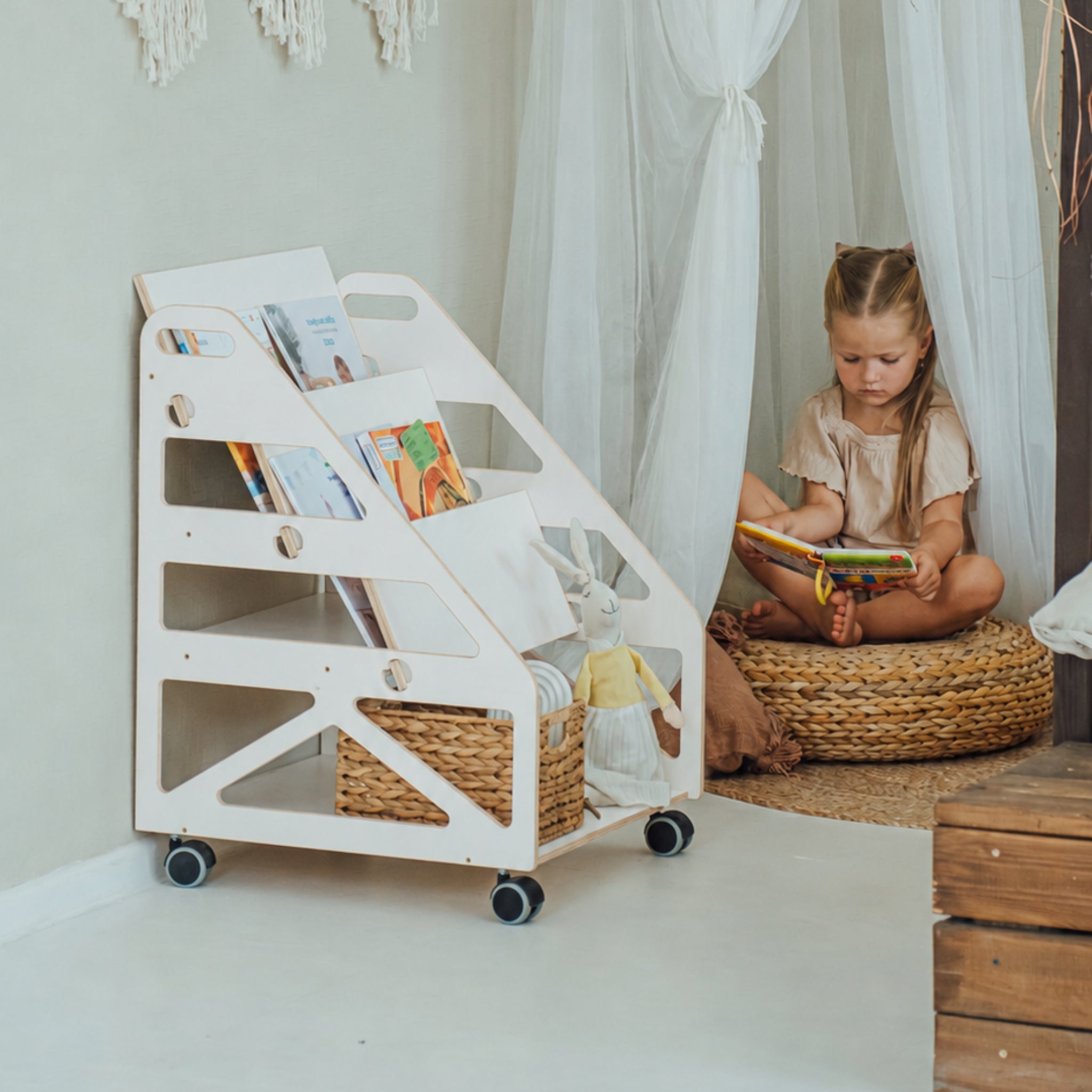 Child sitting in a white 3-in-1 Montessori bookshelf reading chair