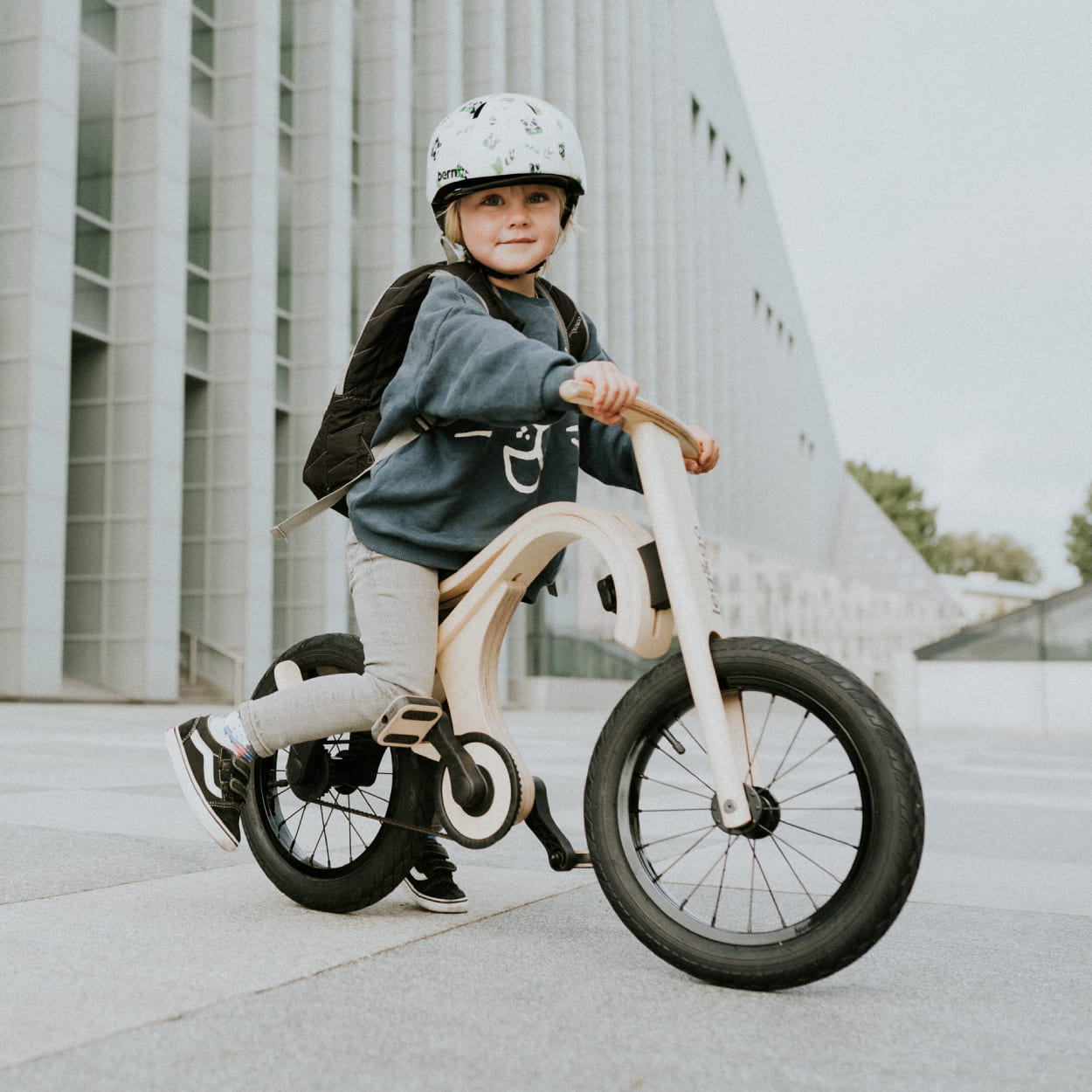 Child riding wooden balance bike with pedal bike add on.