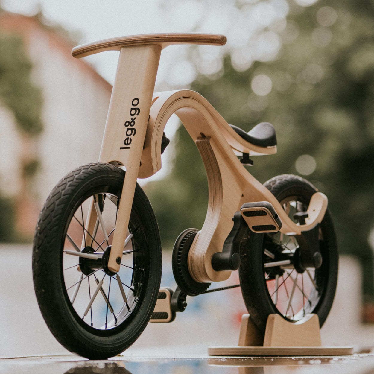 Leg&go pedal bike add on attached on wooden balance bike secured on bike stand.