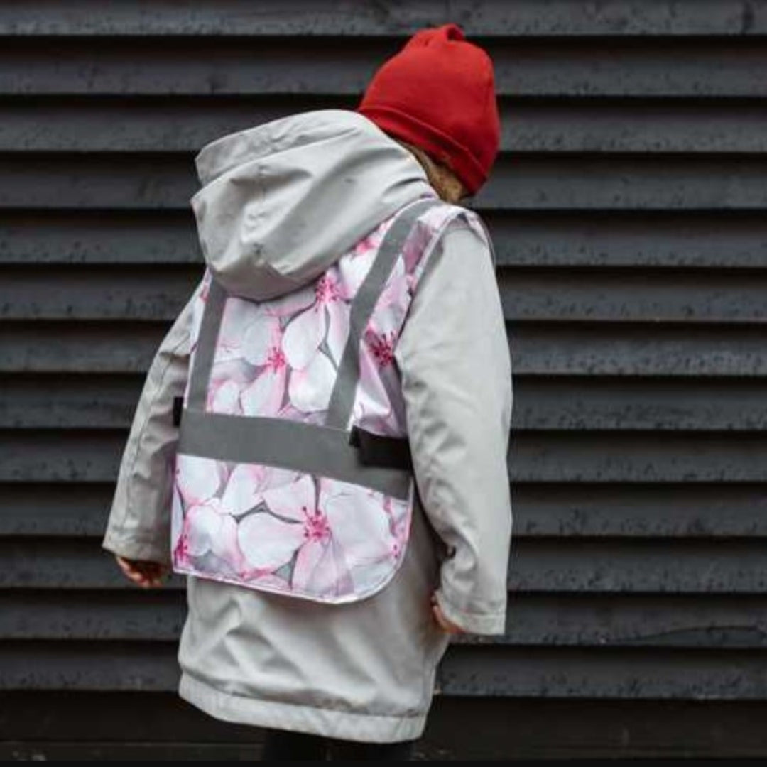 Child in Blossom patterned reflective vest playing outside, designed for safety and style
