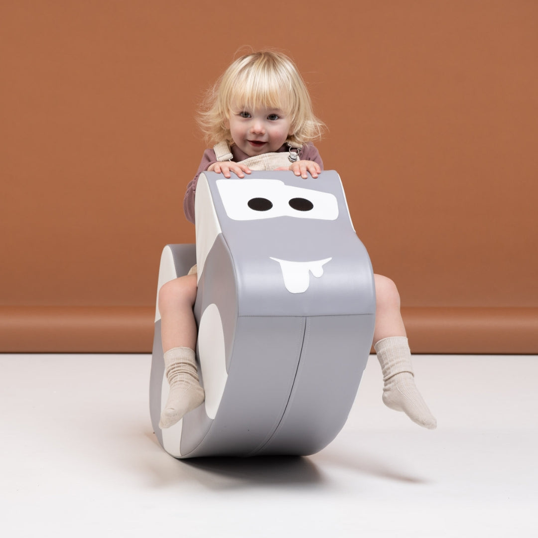 oddler riding gray soft play rocker car, developing coordination and balance in playful way
