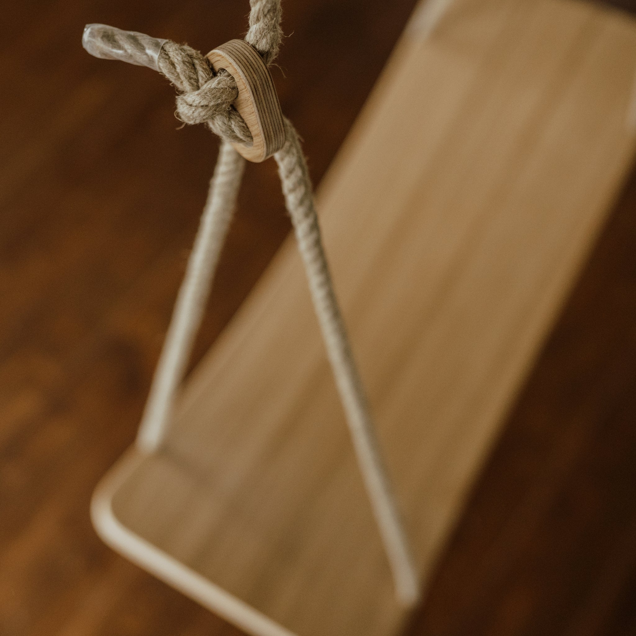 Close-up of rope and knot detail on wooden swing board
