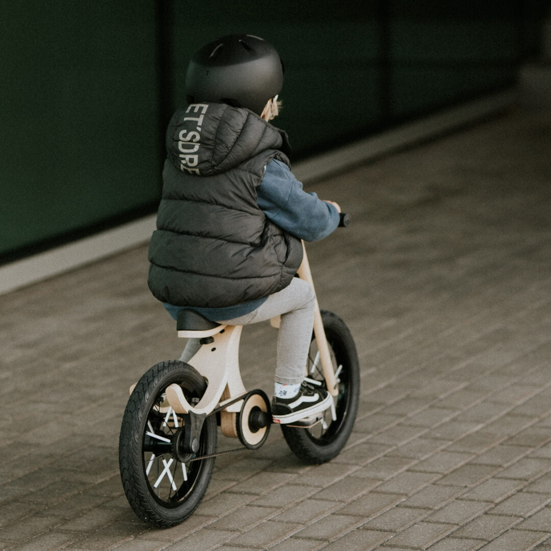 Wooden balance bike in motion with safety spoke reflectors installed on wheels