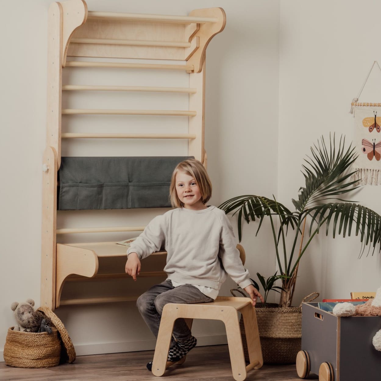 child sitting next to the Swedish ladder turned into a desk space for child with a desk and chair add on