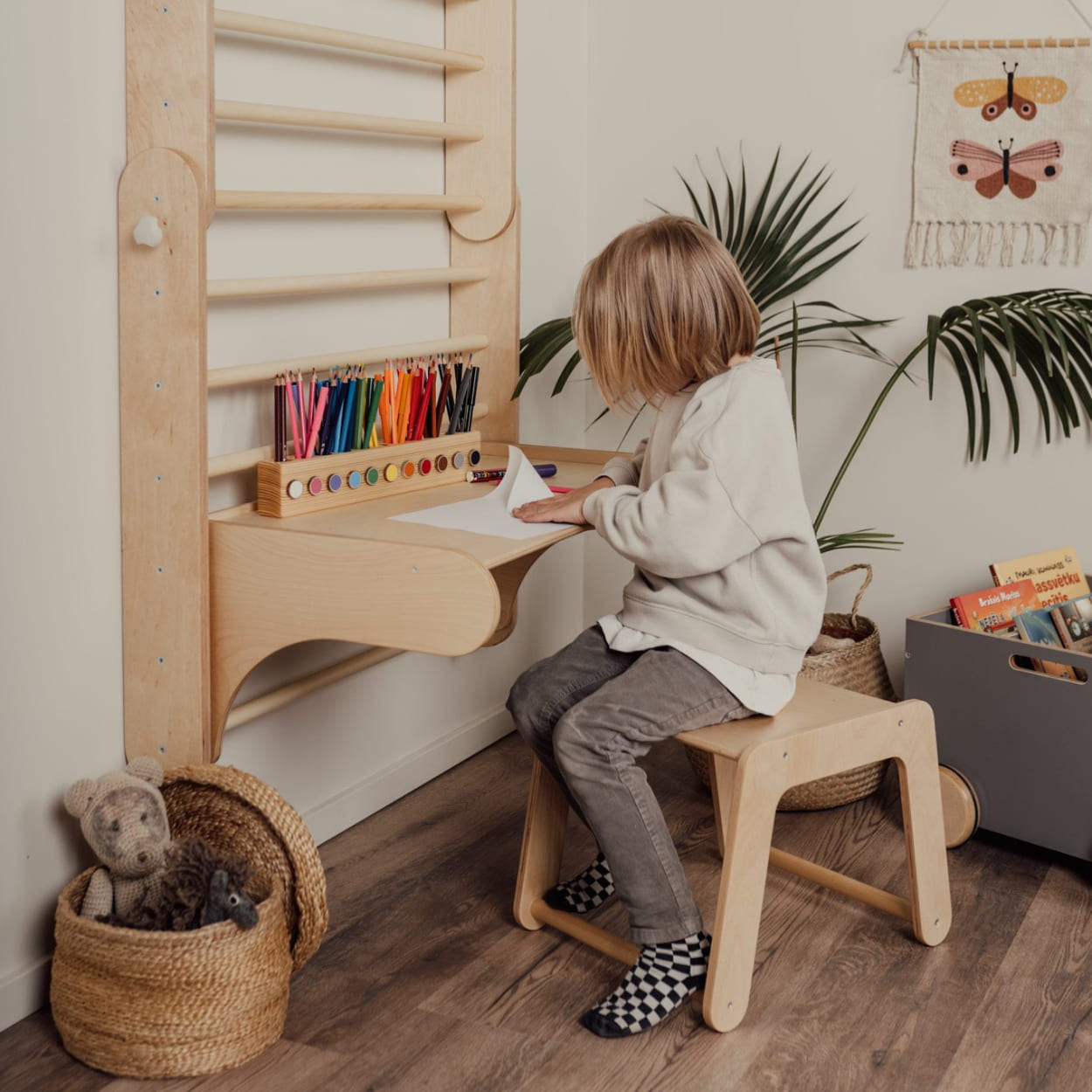 Boy doing arts and crafts in a cozy space next to a desk that's a part of swdish wall climber gym.