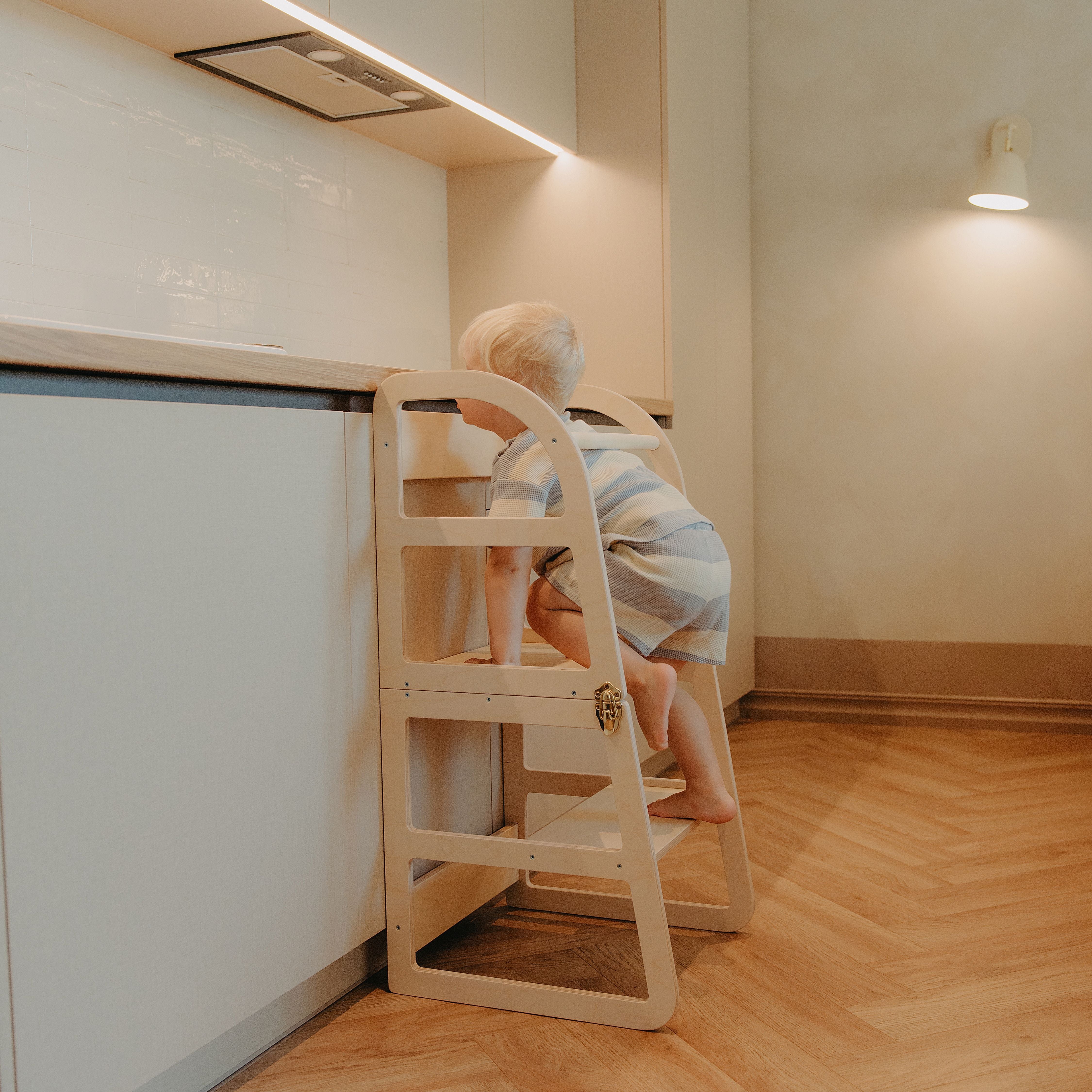 Toddler using a transformable kitchen tower to safely climb up and reach the kitchen countertop