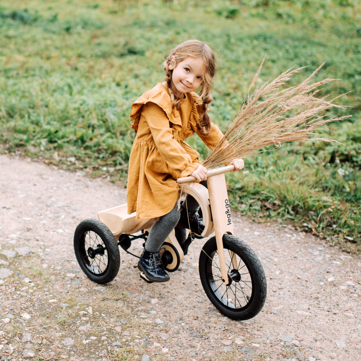 Girl riding wooden tricycle down the road
