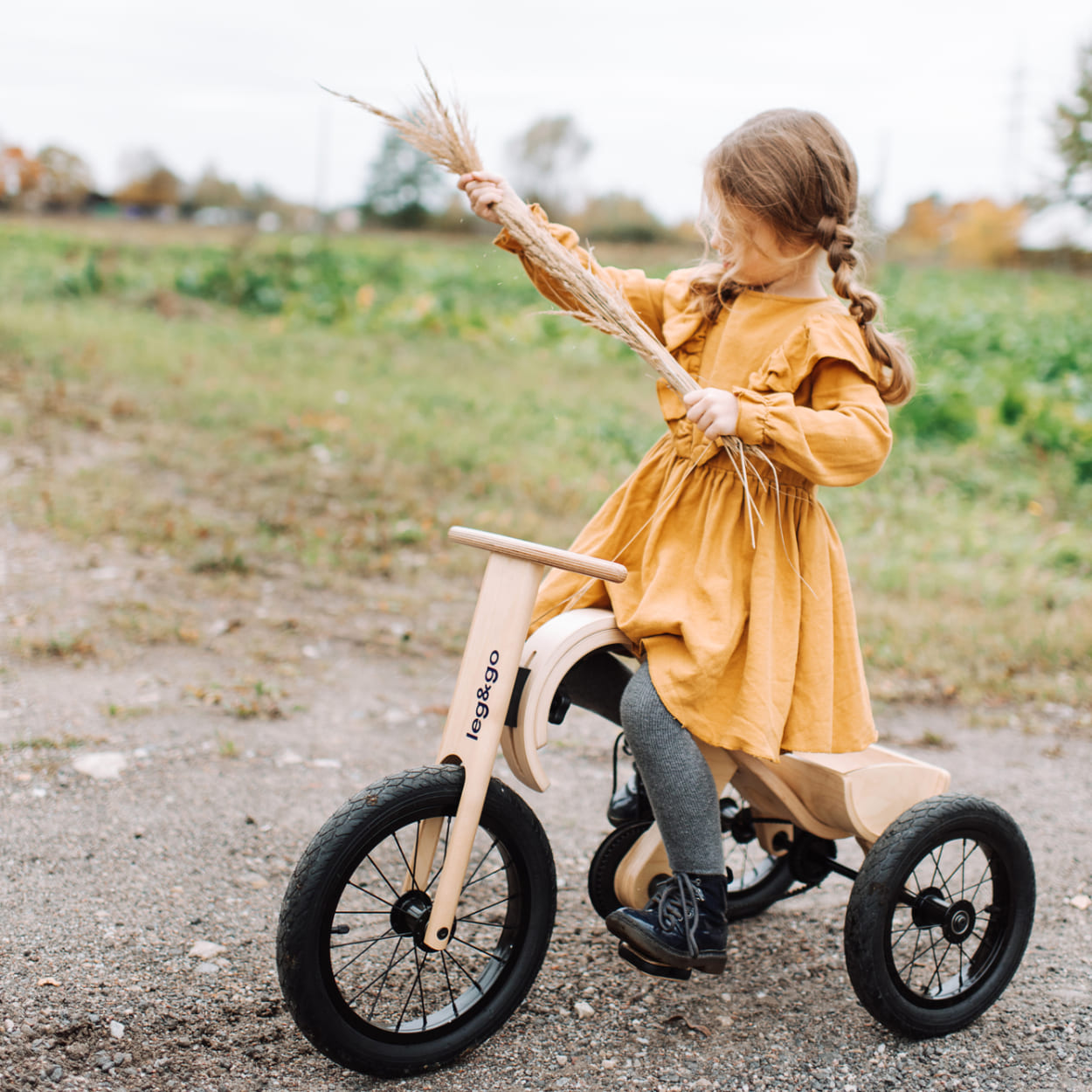 Girls sitting on a wooden tricycle made by leg&go