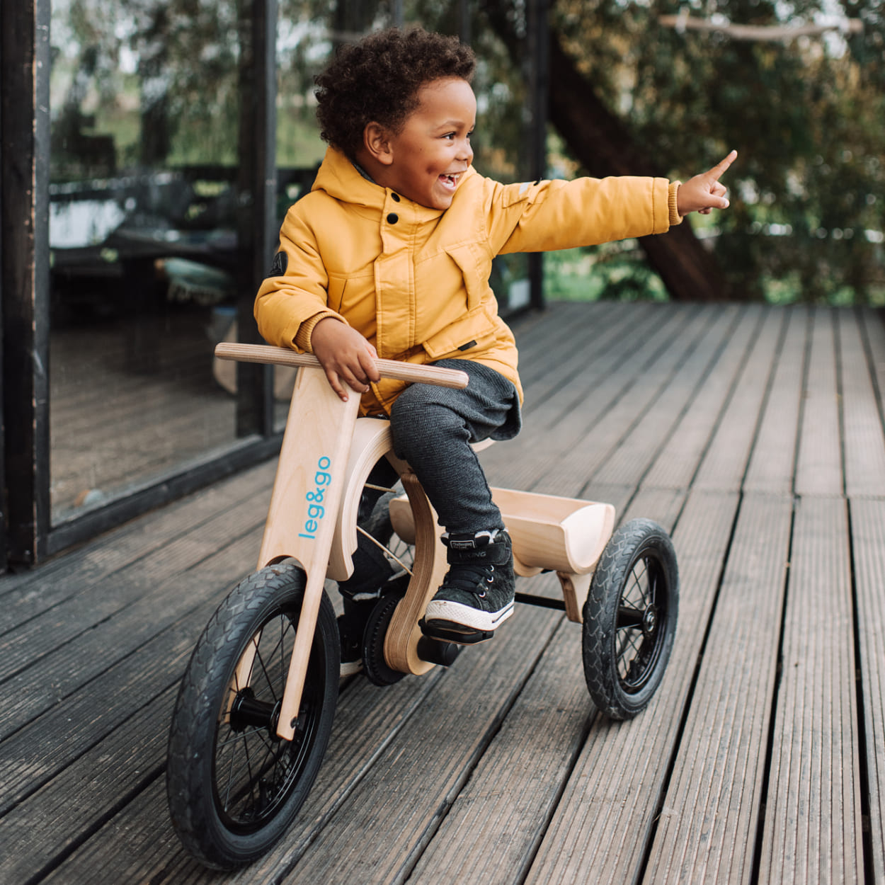 Boy sitting on a leg&go tricycle and looking around