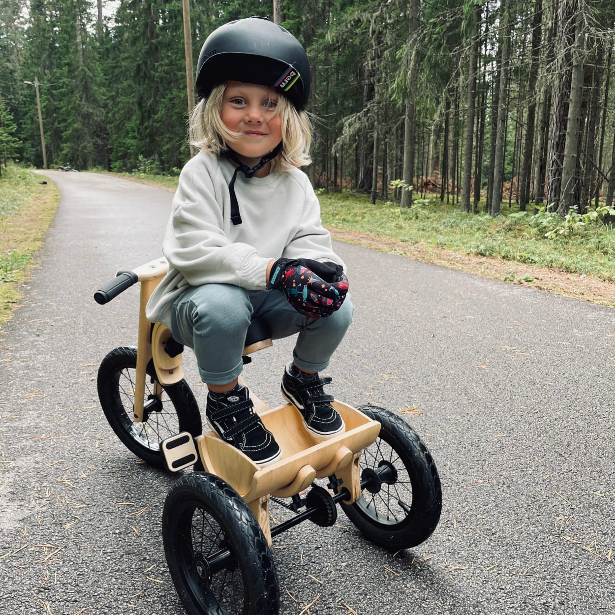 Child sitting backwards on his wooden tricycle on a race track