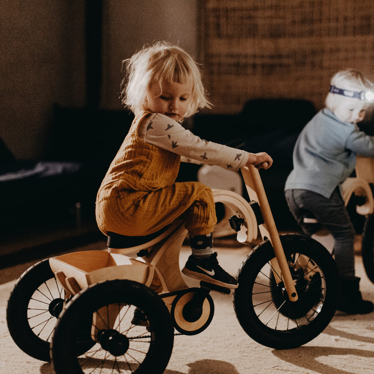 child riding wooden tricycle indoors