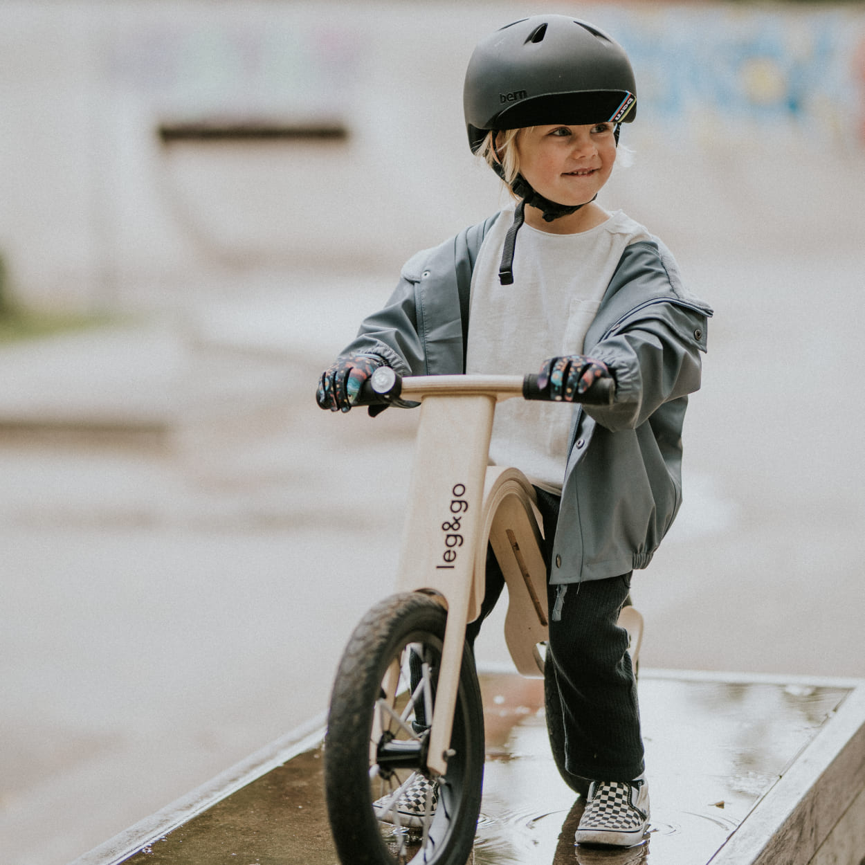 Boy sitting on Wooden balance bike in skatepark