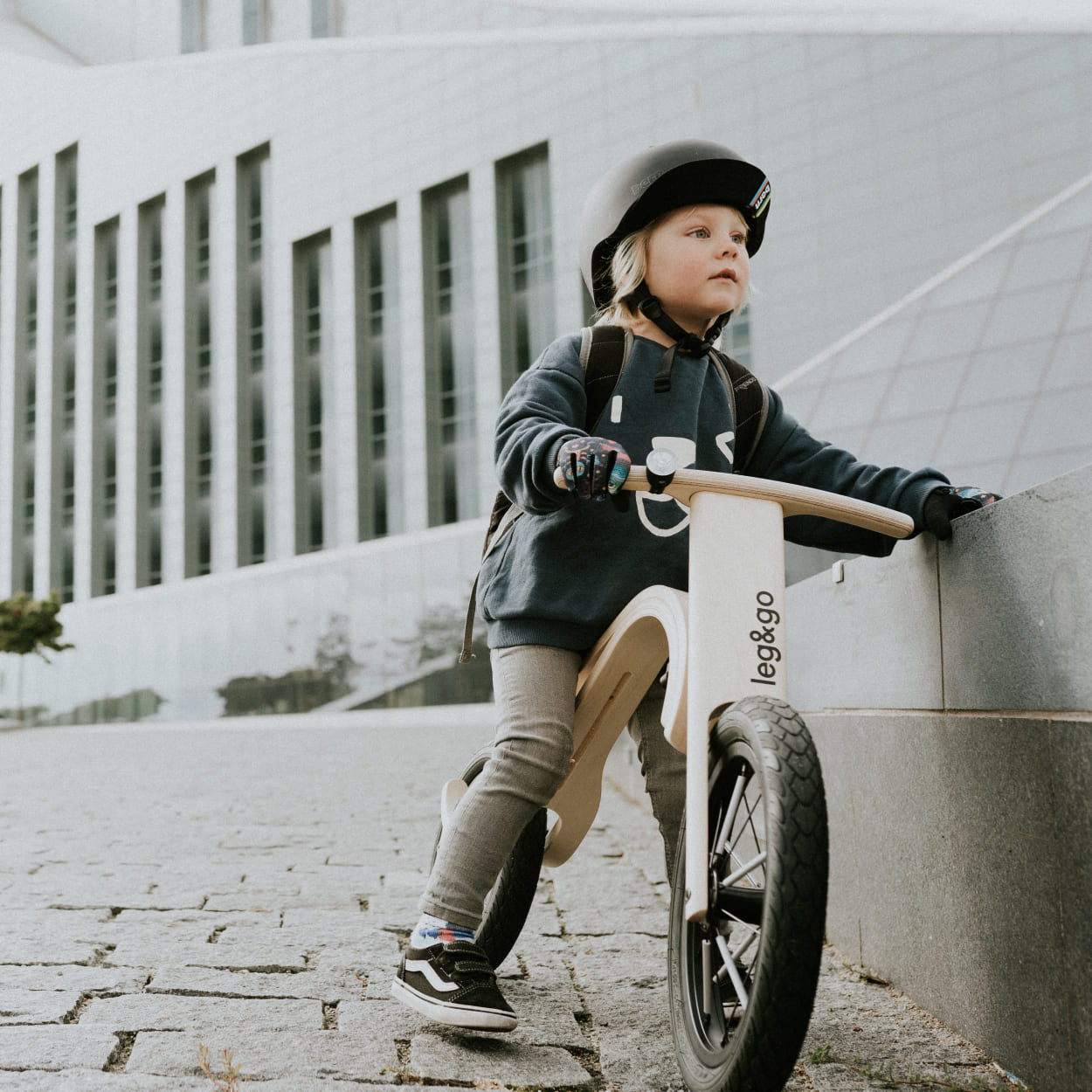 Child sitting on a balance bike in urban place