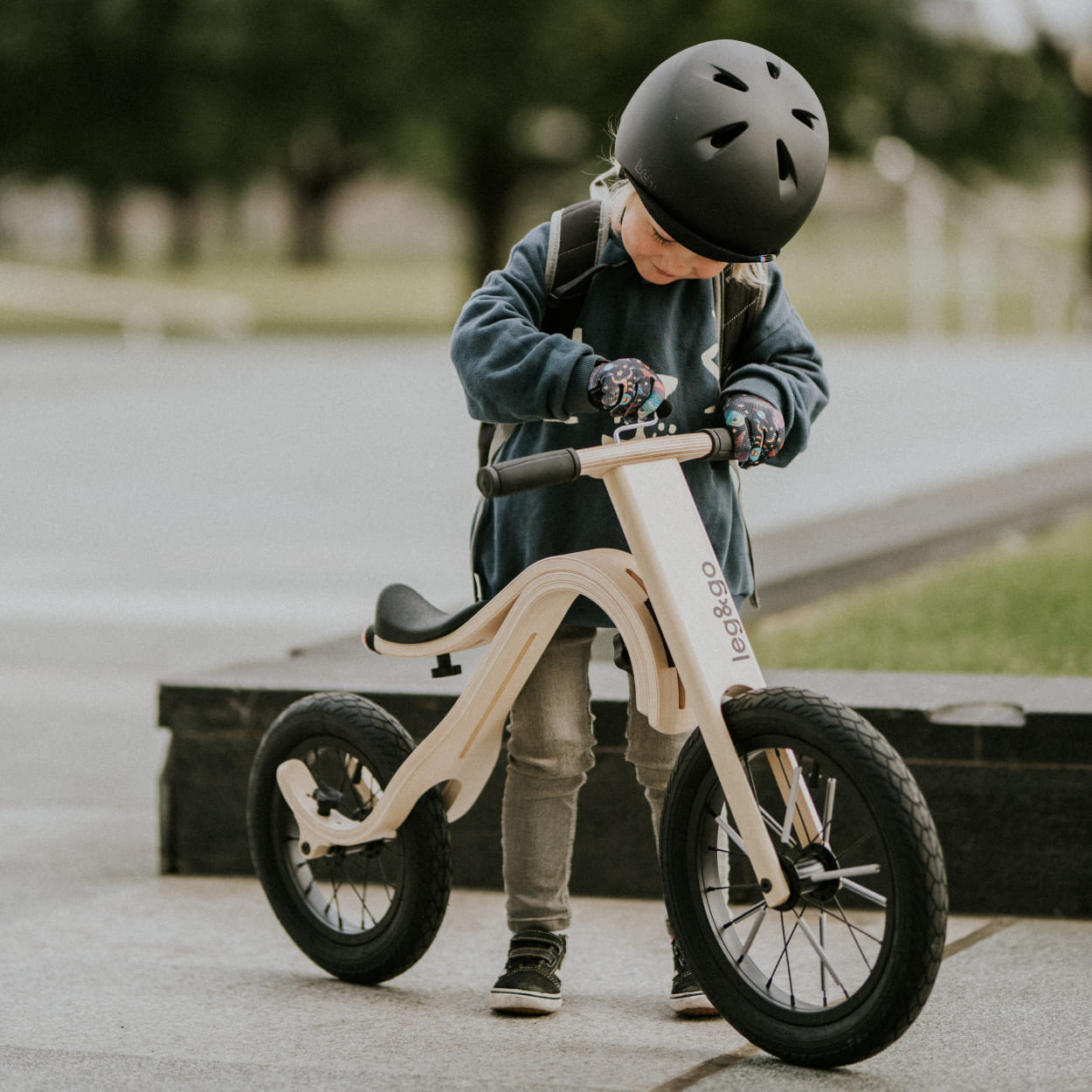Kid inspecting his wooden balance bike