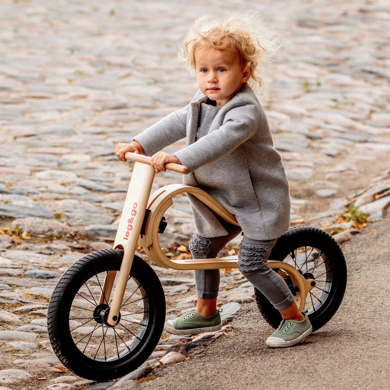 Child sitting on bouncy wooden balance bike