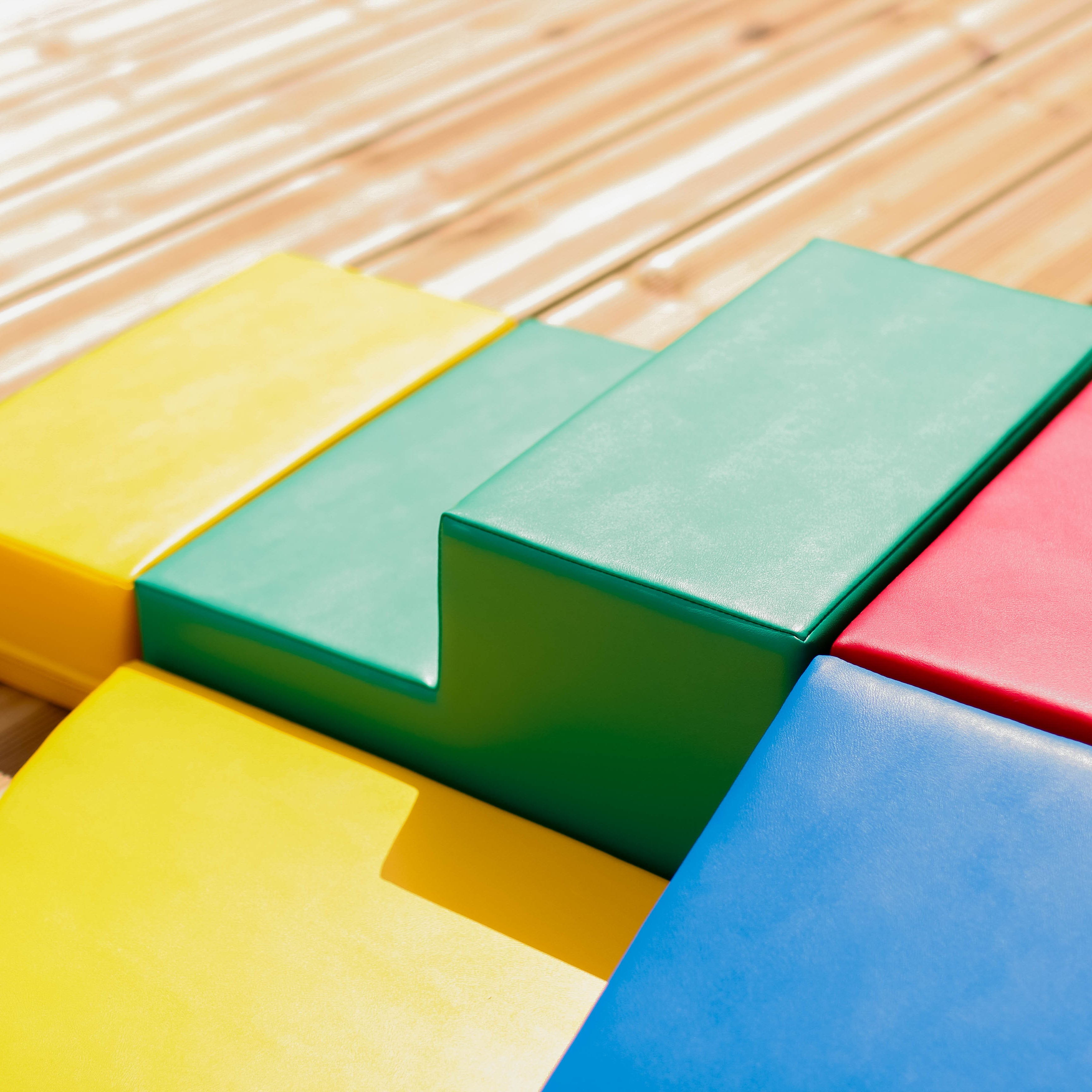 Close-up of multicolor soft play corner blocks on wooden floor, showing texture and vibrant colors