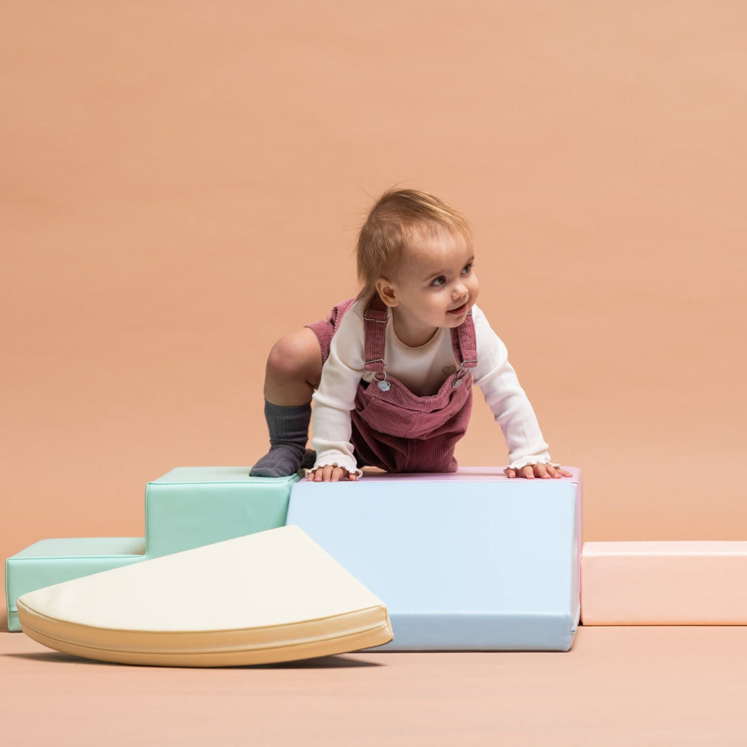 Toddler exploring and climbing on pastel soft play foam corner climber set