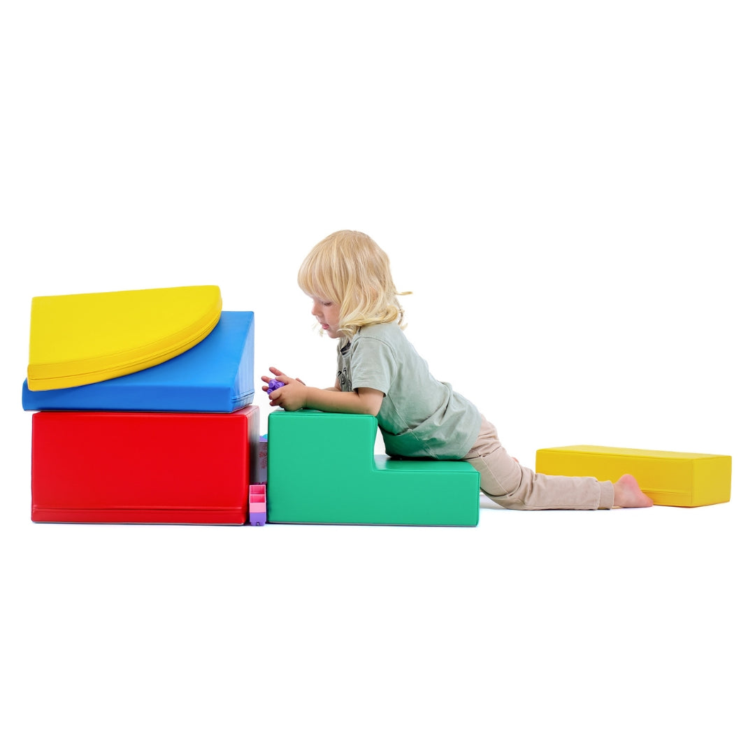 Toddler climbing on a multicolor soft foam play set, exploring with hands and knees on corner-shaped blocks