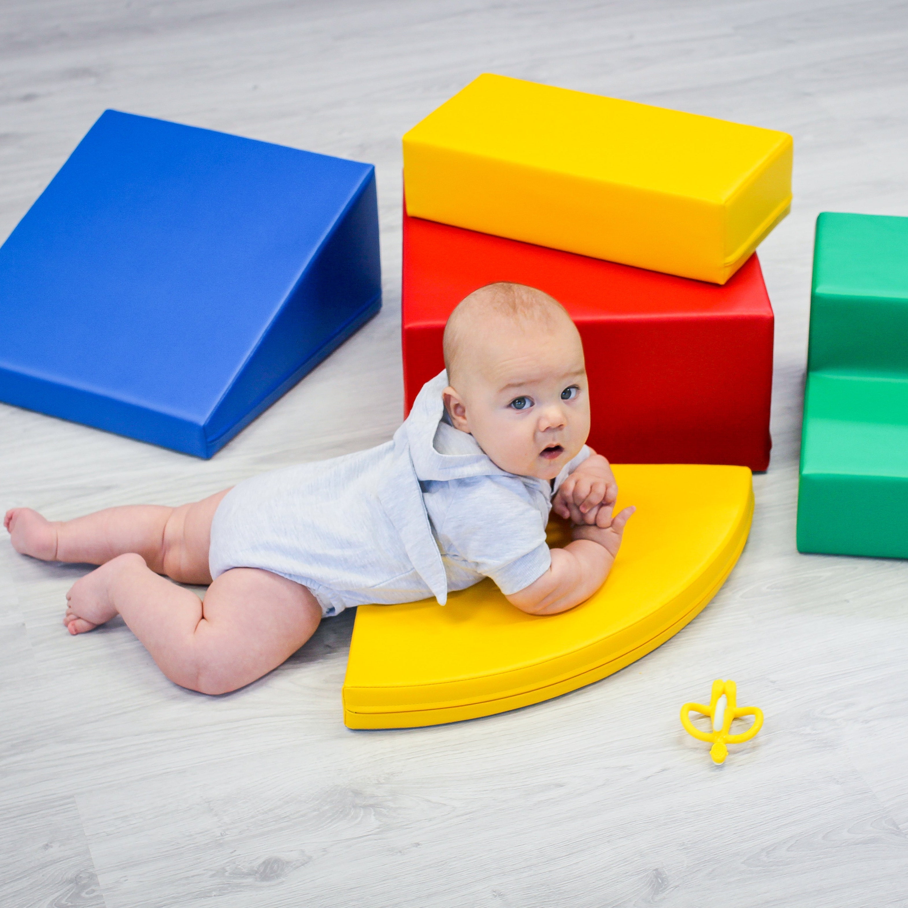 Baby crawling and exploring multicolor soft play foam blocks arranged as a corner climber set