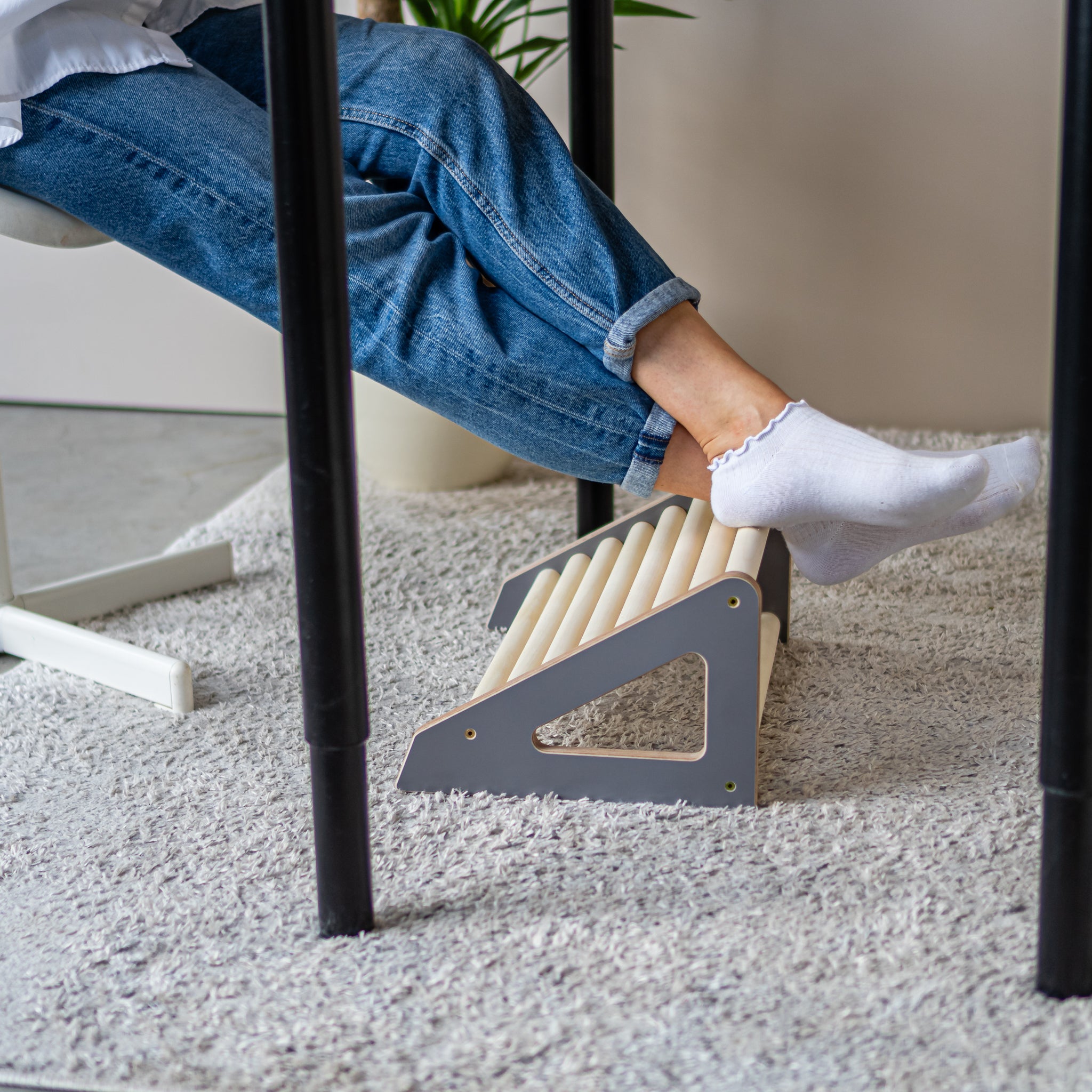 Ergonomic wooden footrest roller supporting feet under a desk
