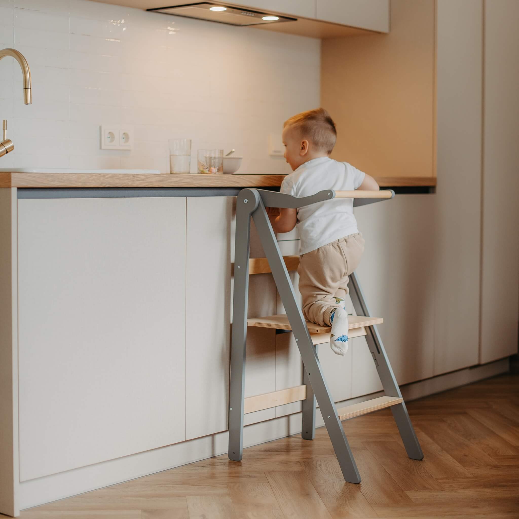 Foldable helper tower used in modern kitchen to support toddler independence