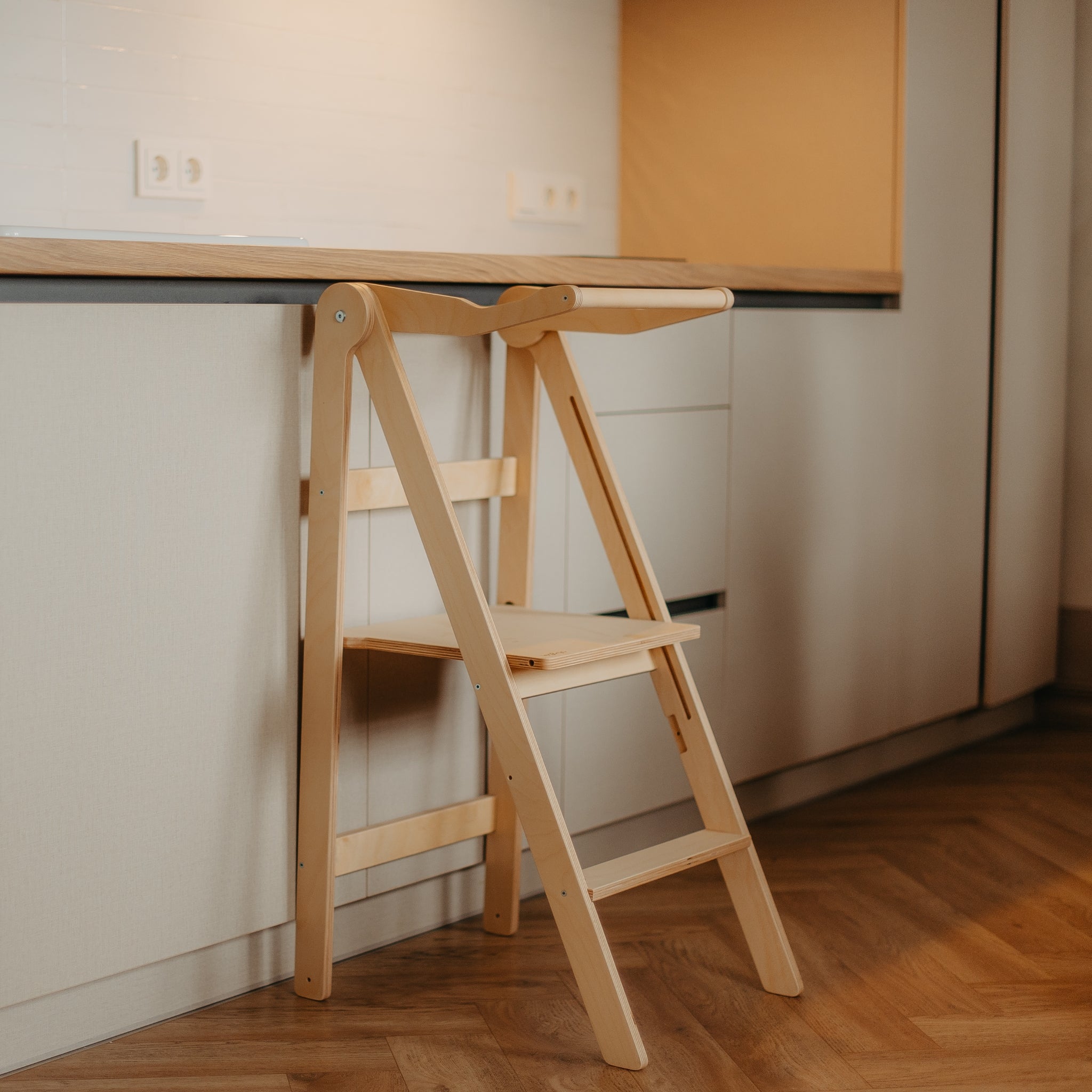 Foldable wooden learning tower in natural color placed in modern home interior