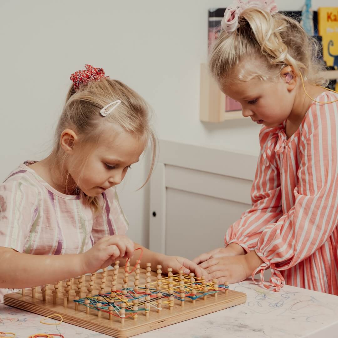 Two children playing with wooden Montessori geoboard – multiplication board and math learning toy
