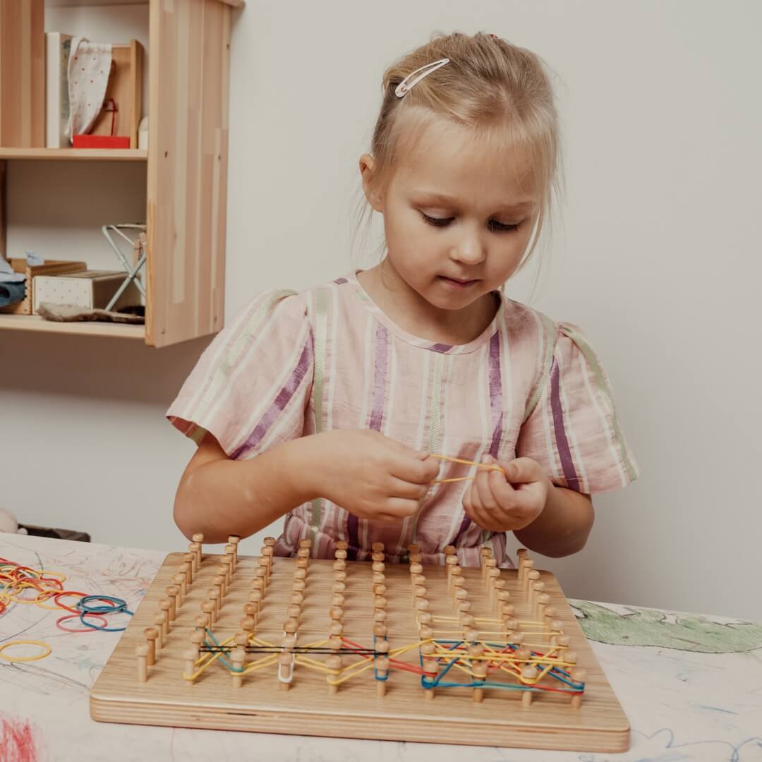 Child using wooden geoboard pegboard – Montessori toy and math activity board