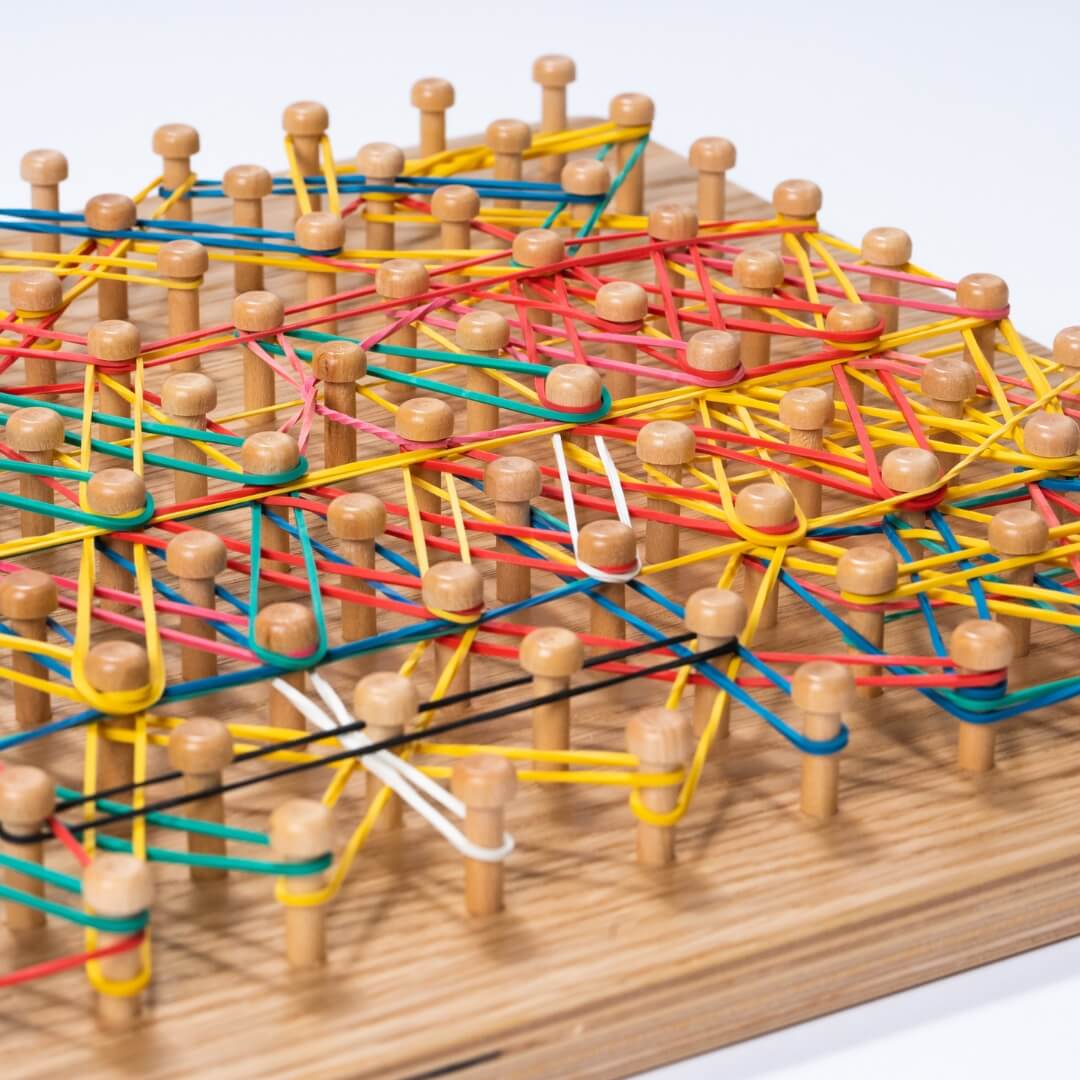 Colorful rubber bands on wooden geoboard – Montessori math manipulative and activity board