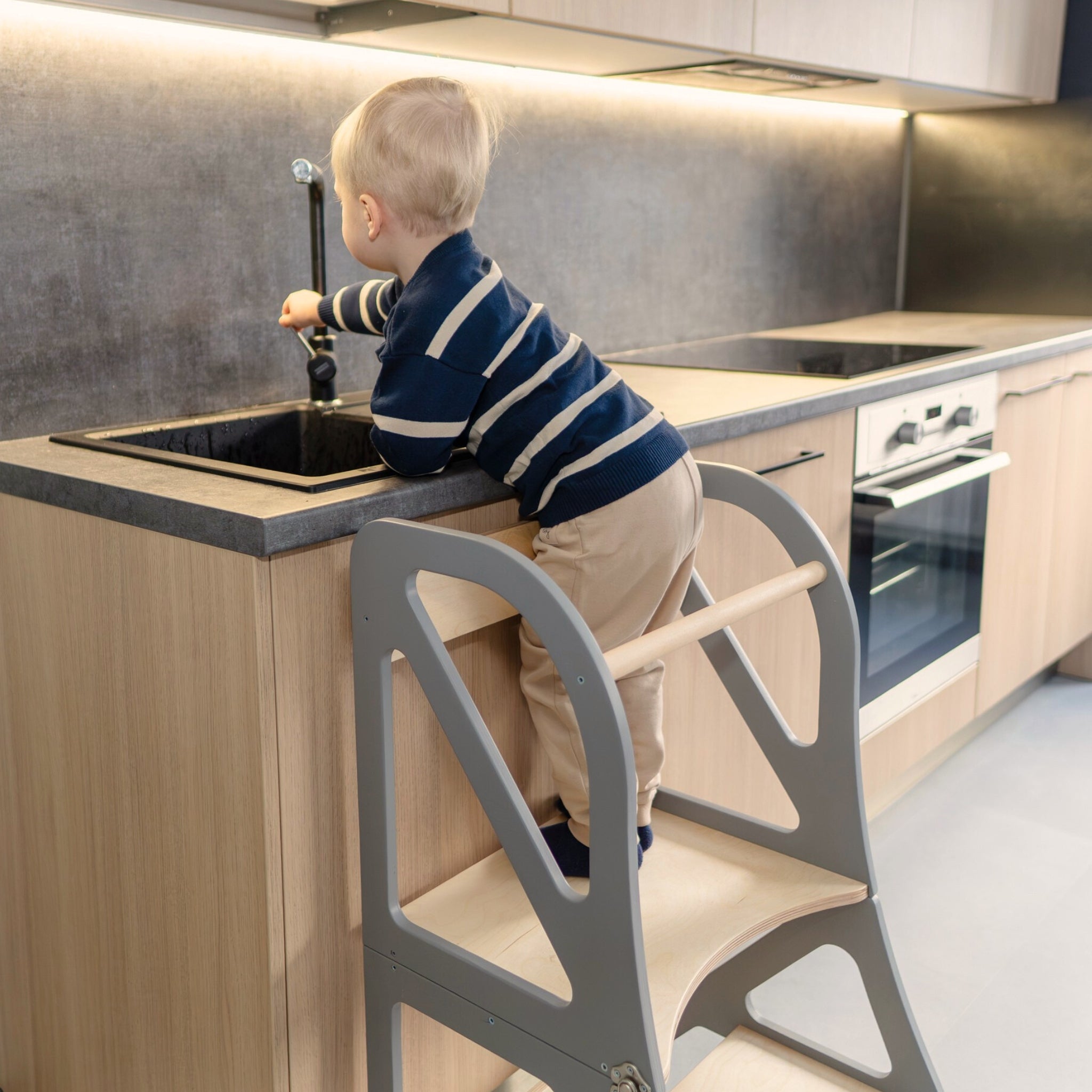 Child using transformable kitchen tower at counter in standing mode